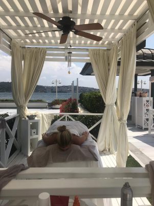 Pergola altında deniz manzaralı masaj yatağında dinlenen kadın