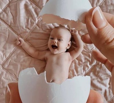 Yumurta kabuğundaki neşeli bebek ve ona uzanan el