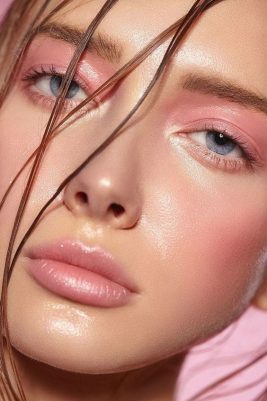 Pembe makyajlı, ıslak saç telleri ve mavi gözlü genç bir kadın portresi