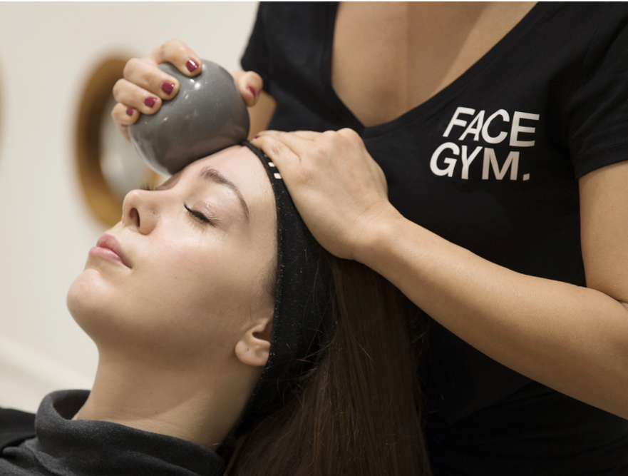 Yüz bakımı alan kadın, terapist alnına FaceGym aletiyle masaj yapıyor