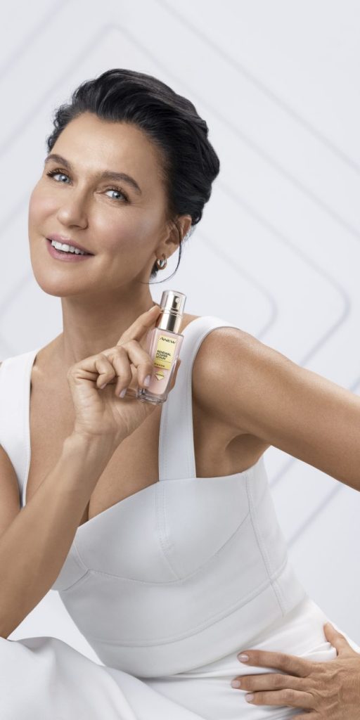 Anew serum tutan beyaz giysili, gülümseyen kadın portresi
