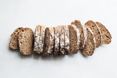Beyaz zeminde unlu, dilimlenmiş koyu renkli ekmek üstten görünüm