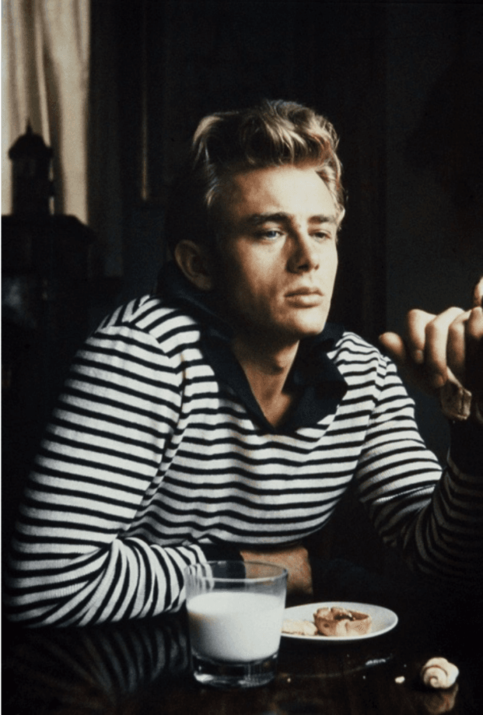 James Dean çizgili kazakla masada düşünceli, süt ve pasta önünde