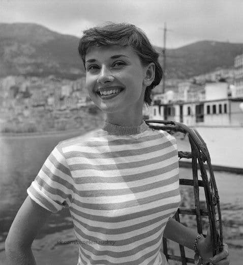 Gülümseyen Audrey Hepburn çizgili tişörtüyle deniz manzarası önünde