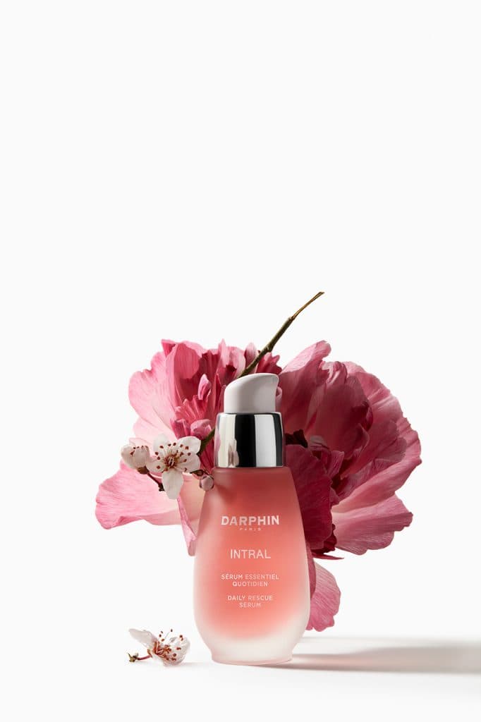 Darphin Intral serum pembe çiçeklerle beyaz fon üzerinde sergileniyor