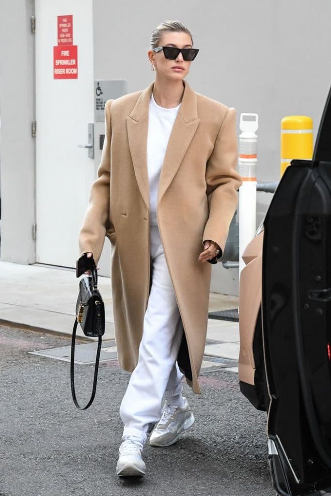 Hailey Bieber camel palto, beyaz eşofman, siyah güneş gözlüğü, el çantası
