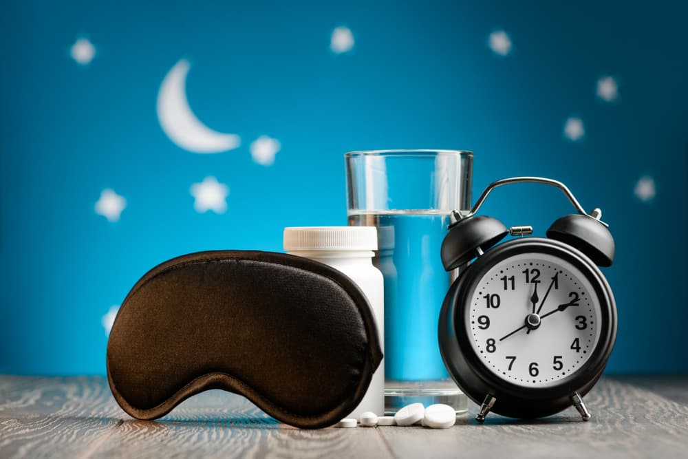 Uyku maskesi, haplar, su ve çalar saat ile gece temalı düzenleme