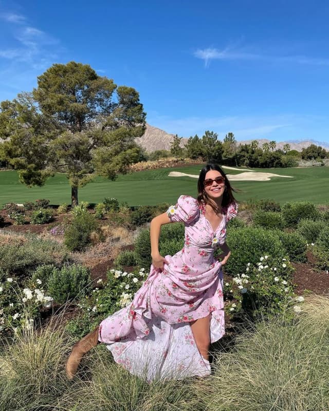 Gülümseyen Kendall Jenner pembe çiçekli elbisesiyle golf sahasında poz veriyor