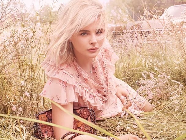 Chloë Grace Moretz pembe elbiseyle çiçekli tarlada oturuyor