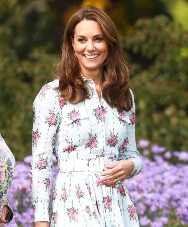Kate Middleton gülümsüyor açık mavi çiçekli elbiseyle dışarıda