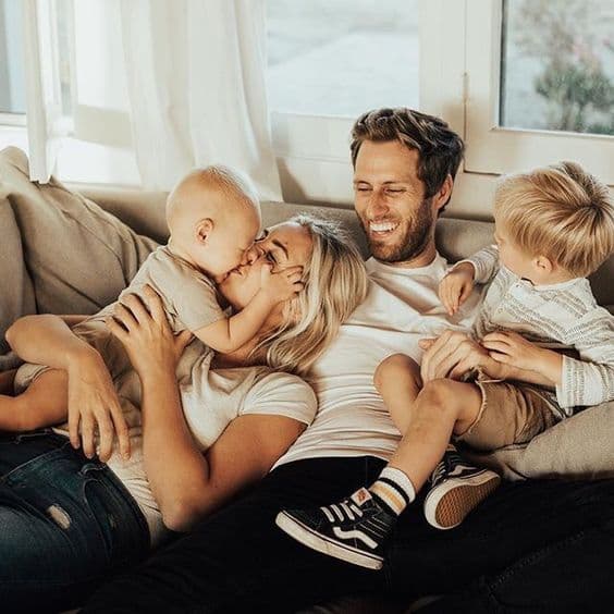 Mutlu bir aile kanepede sevgiyle sarılırken gülüşüyor