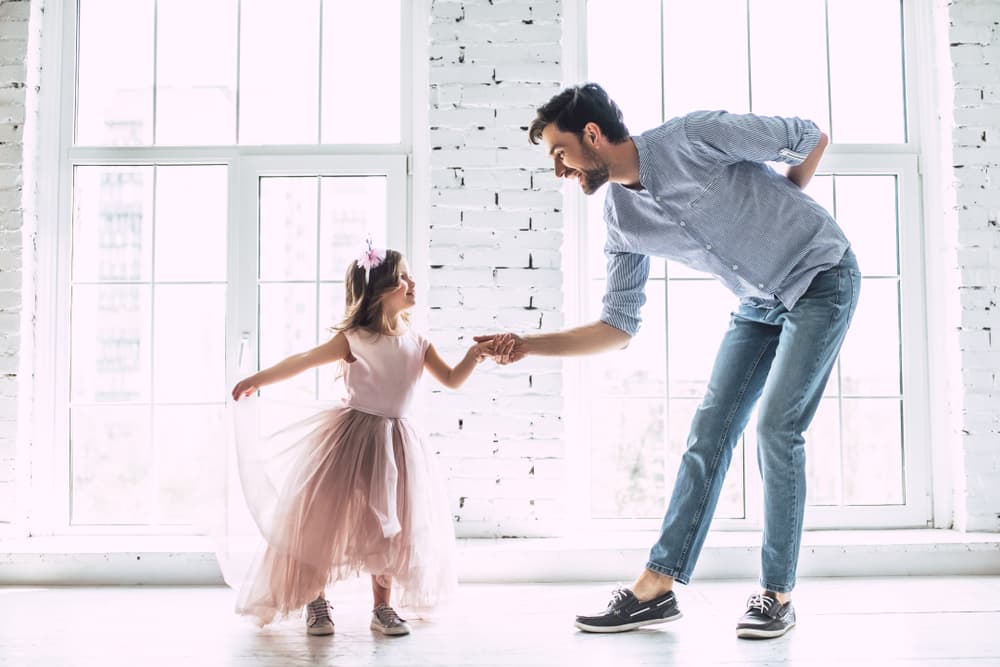 Mutlu baba ve kızı aydınlık pencere önünde el ele dans ediyorlar