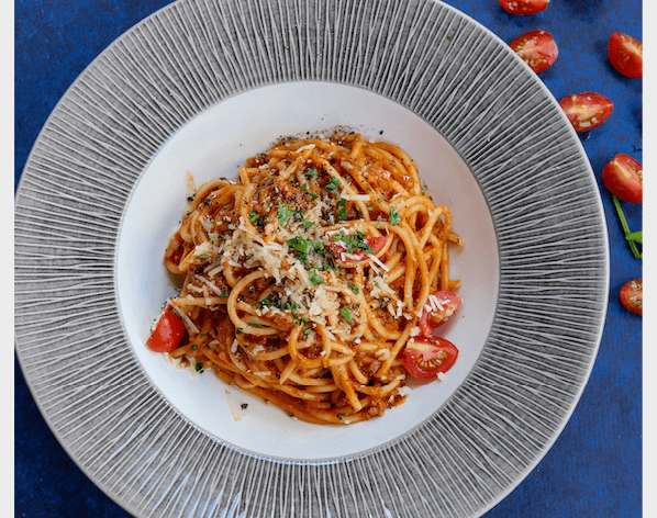 Mavi zeminde domates ve parmesanlı iştah açıcı spagetti tabağı