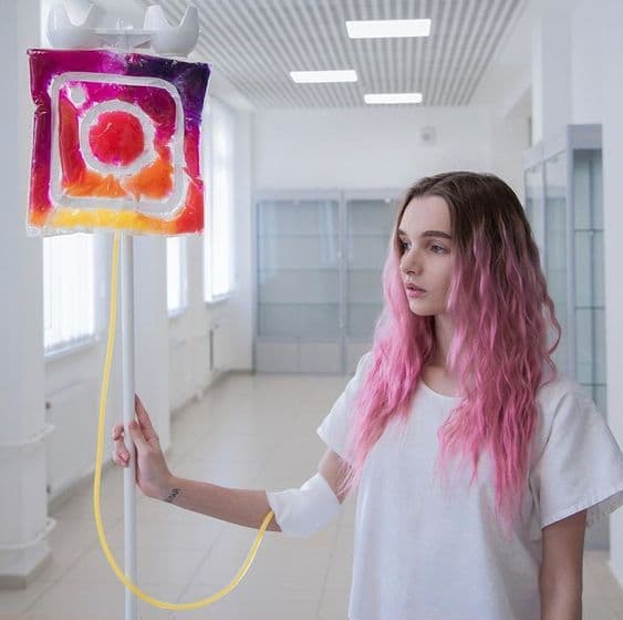 Pembe saçlı kadın Instagram logosu serumu takılı hastane koridorunda