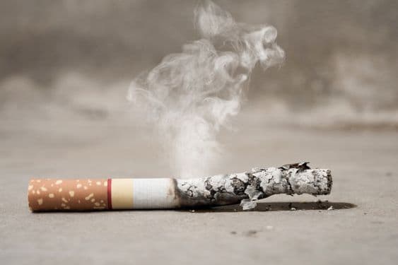 Yanan sigara uzun külü ve havaya yükselen dumanı