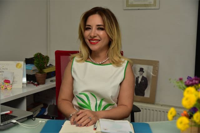 Ofis ortamında masasında oturan gülümseyen sarışın bir kadın