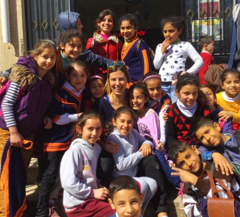 Dışarıda birçok gülümseyen çocuk ve onlarla bir kadın