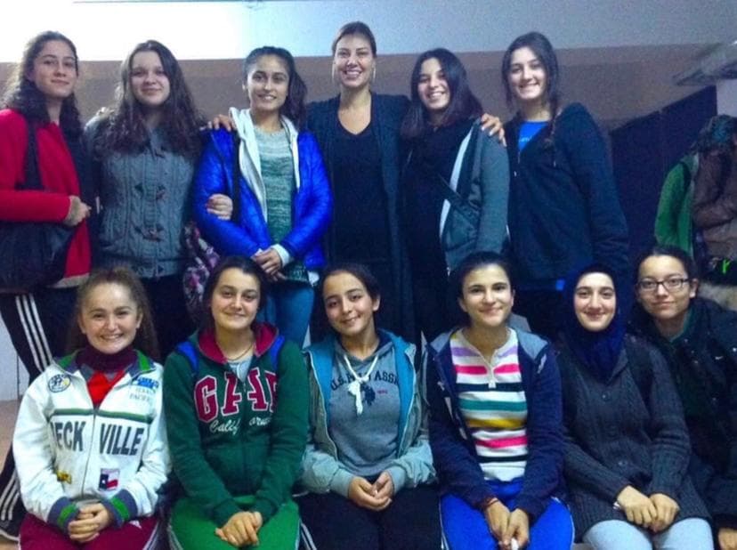 Bir yetişkinle birlikte poz veren neşeli genç kadınlar grubu