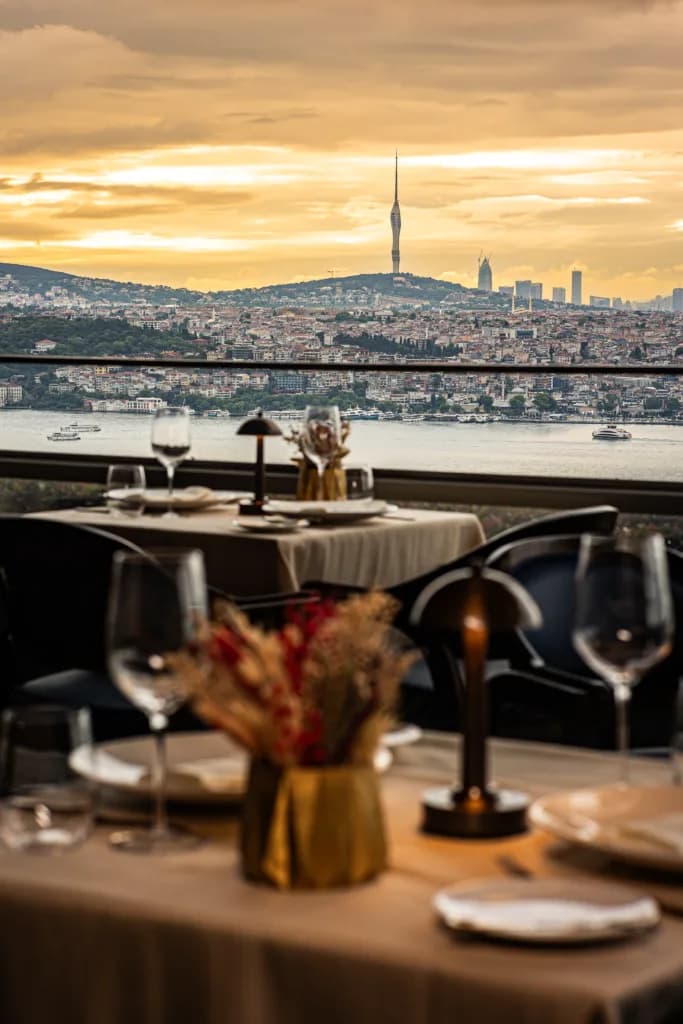 Gün batımında İstanbul boğazı ve Çamlıca Kulesi manzaralı restoran masası