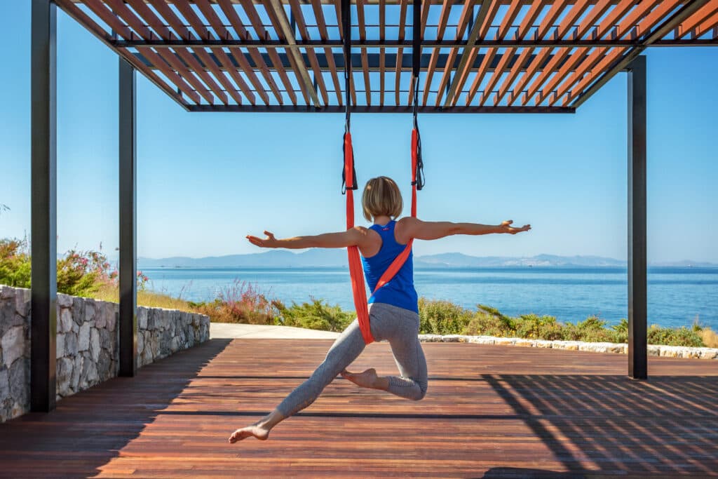 Deniz kenarında pergoleda hamak yogası yapan bir kadın