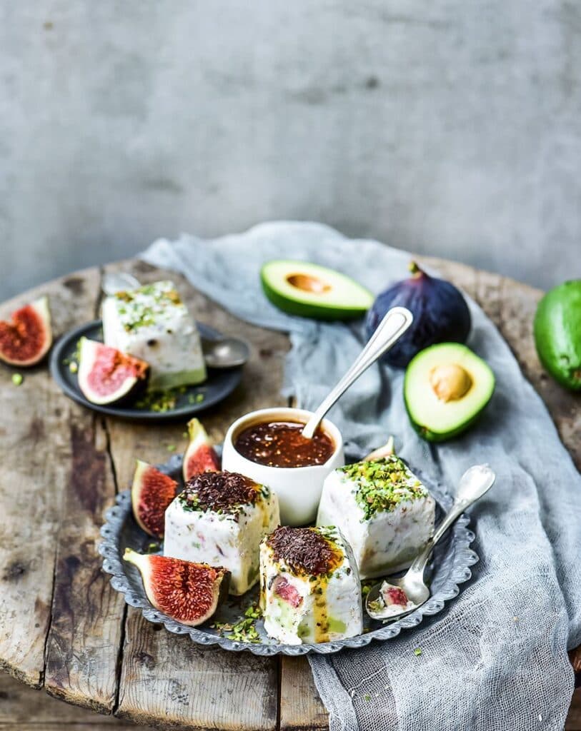 Ahşap masada incir, avokado ve sos ile kremalı tatlılar
