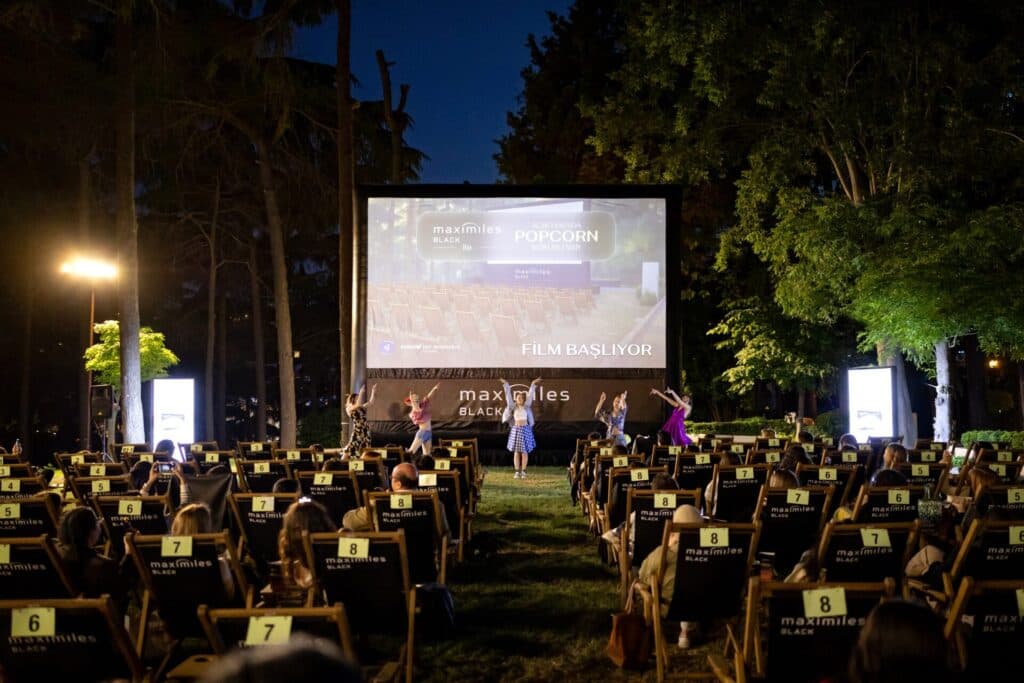 Gece açık hava sinemasında dansçıların performansı ve film gösterimi