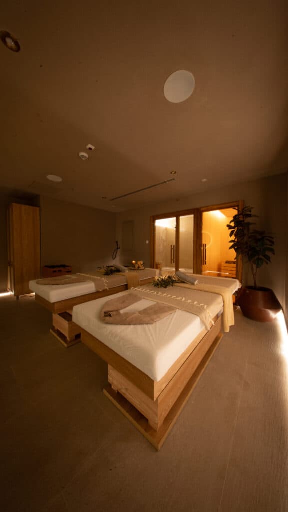 Ahşap masaj yatakları ve saunası olan loş ışıklı spa odası