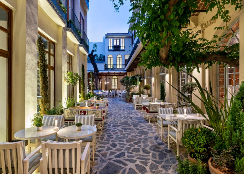 Taş zeminli avluda bitkiler ve masalarla dolu şık bir restoran