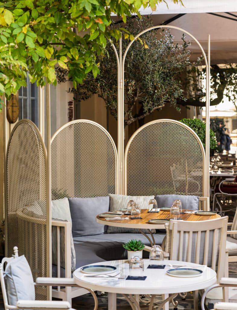 Yeşillikler içinde modern bir dış mekan restoranında şık masalar ve oturma düzeni