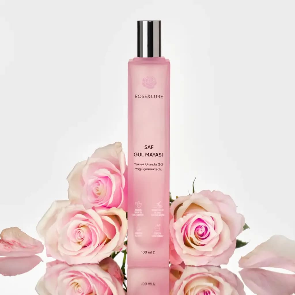 Rose&Cure gül mayası pembe şişesi taze pembe güllerle yansımalı zeminde