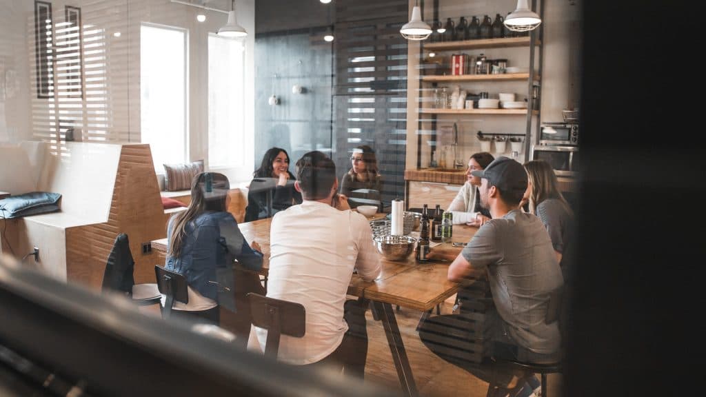 Modern bir ofis masasında sohbet eden bir grup insan