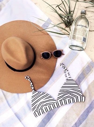 Plajda şapka güneş gözlüğü bikini havlu ve su şişesi