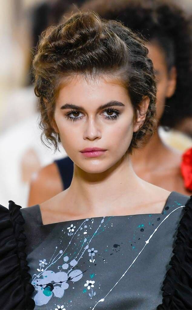 Model Kaia Gerber kısa kıvırcık saç sanatsal makyaj ve desenli elbise