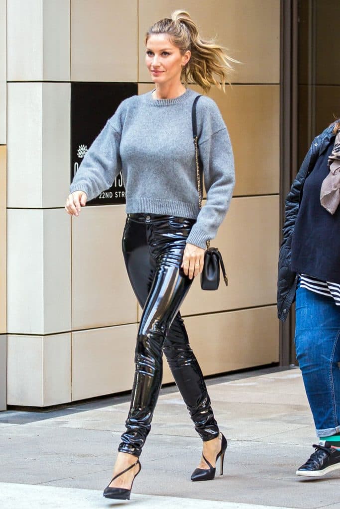 Gisele Bündchen gri kazak ve parlak siyah pantolonla yürürken gülümsüyor