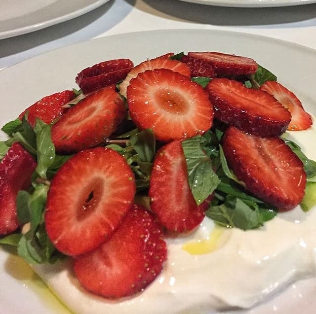 Burrata üzerinde dilimlenmiş çilek roka ve fesleğen salatası