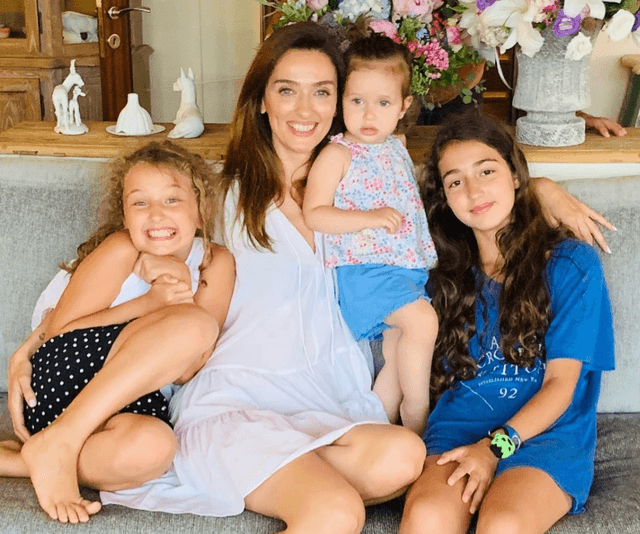 Mutlu anne üç kızıyla kanepede oturmuş gülümsüyor
