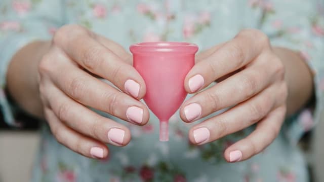 Pembe ojeli eller pembe bir adet kabını yakından gösteriyor