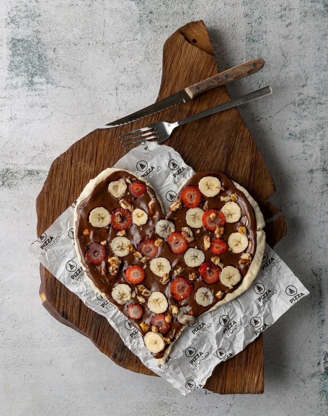 Kalp şeklinde çikolatalı, çilekli ve muzlu tatlı pizza ahşap tahtada