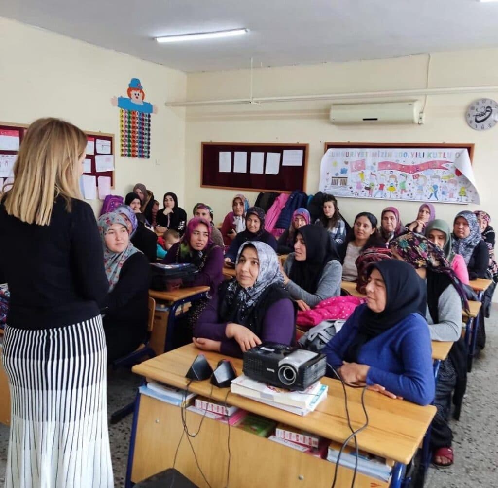 Sınıfta başörtülü kadınlar bir öğretmeni dikkatle dinliyor