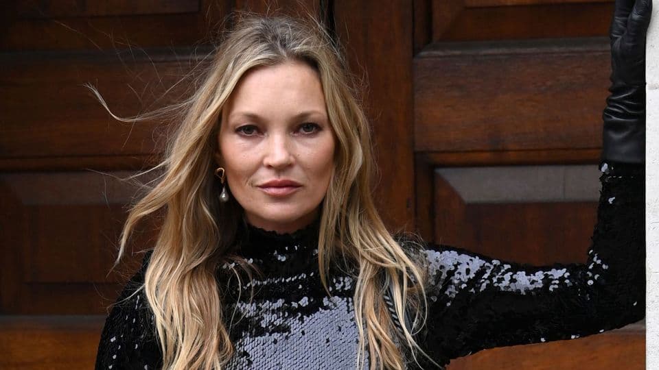Kate Moss siyah pullu üstü ve uzun saçlarıyla kameraya bakıyor