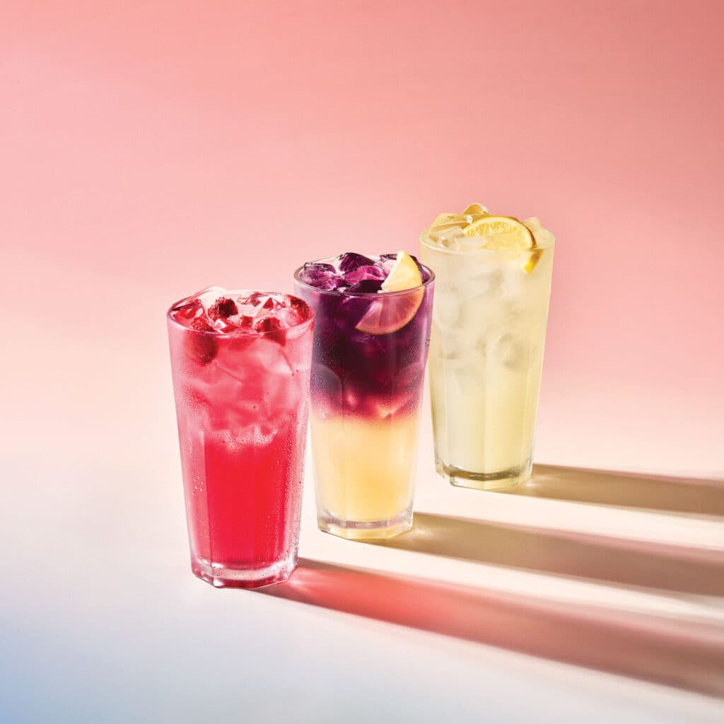 Pembe zeminde üç renkli buzlu limonata ve meyveli içecekler