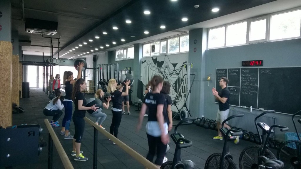 Spor salonunda antrenör eşliğinde medball egzersizi yapan kadınlar grubu