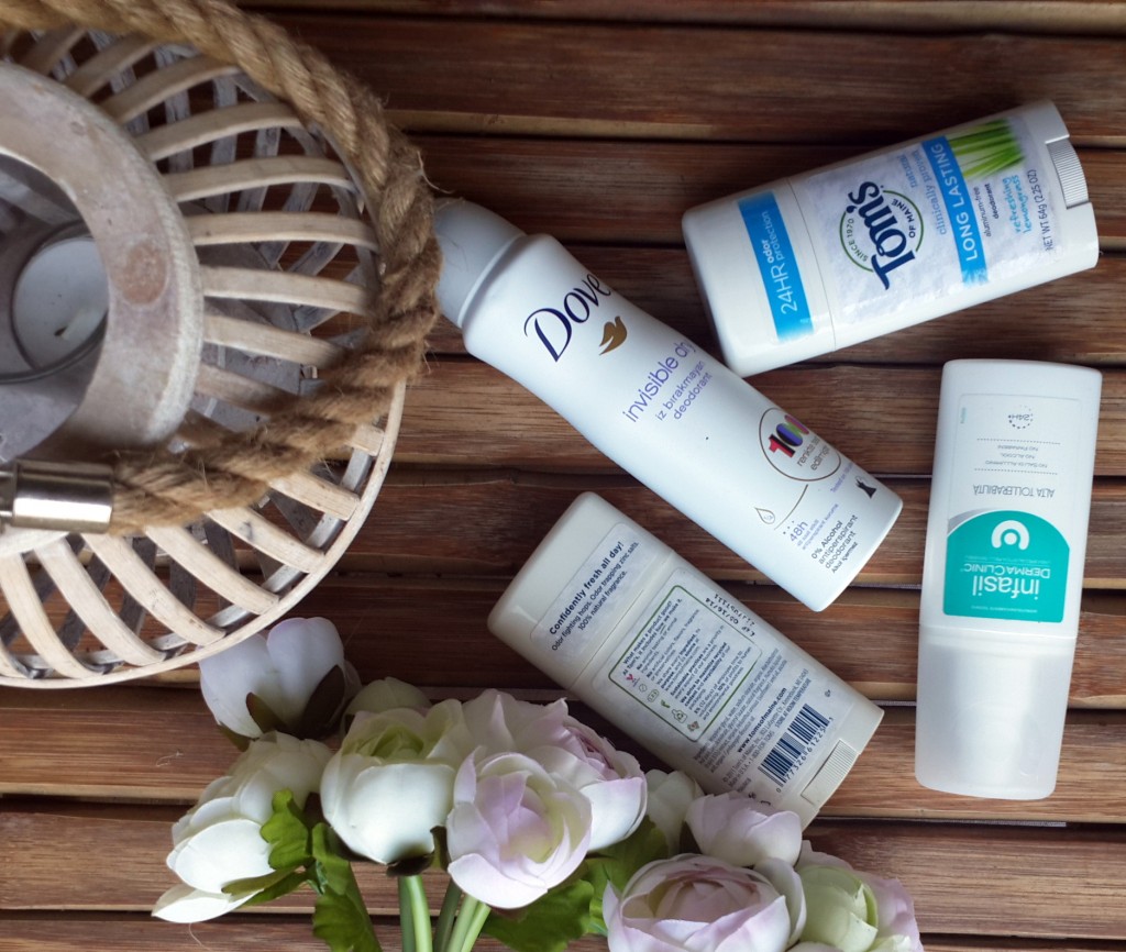 Çeşitli markaların deodorantları, ahşap zeminde çiçekler ve dekoratif sepet