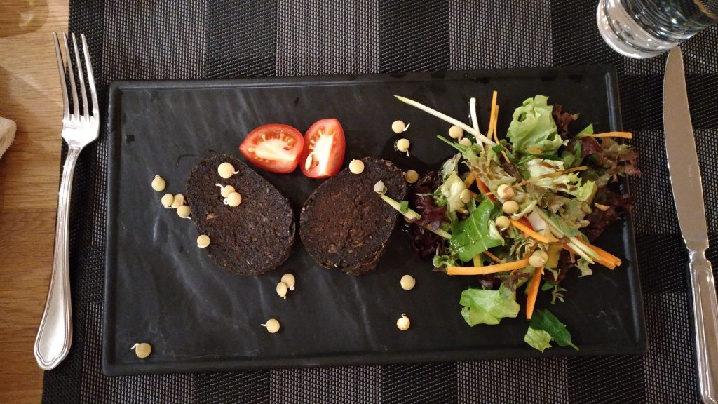 Siyah tabakta kanlı sucuk dilimleri, domates ve taze salata