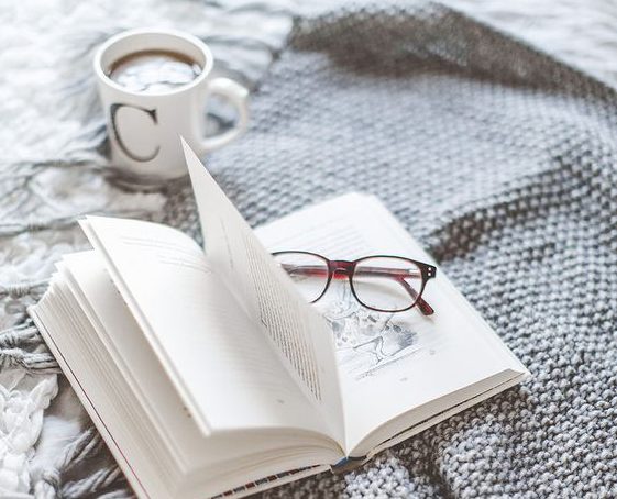 Battaniyede açık kitap gözlük ve C harfli kahve kupası