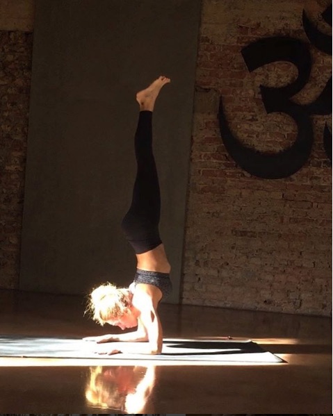 Yoga stüdyosunda kol duruşu yapan kadın om sembolü