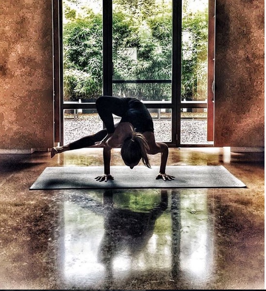 Kapalı bir alanda mat üzerinde zorlu bir yoga pozu yapan kadın