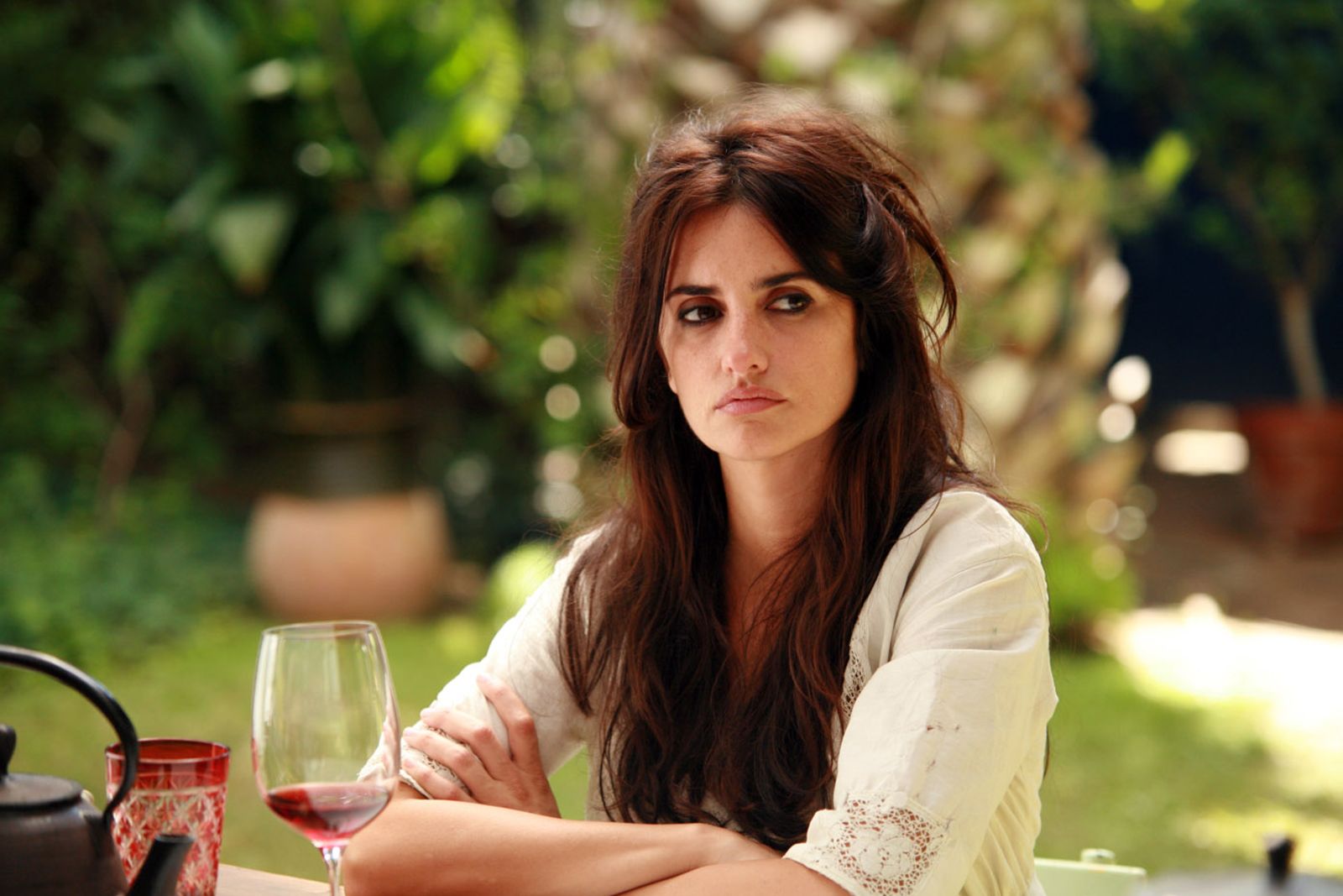 Penélope Cruz bahçede oturmuş, şarap kadehiyle düşünceli bakıyor