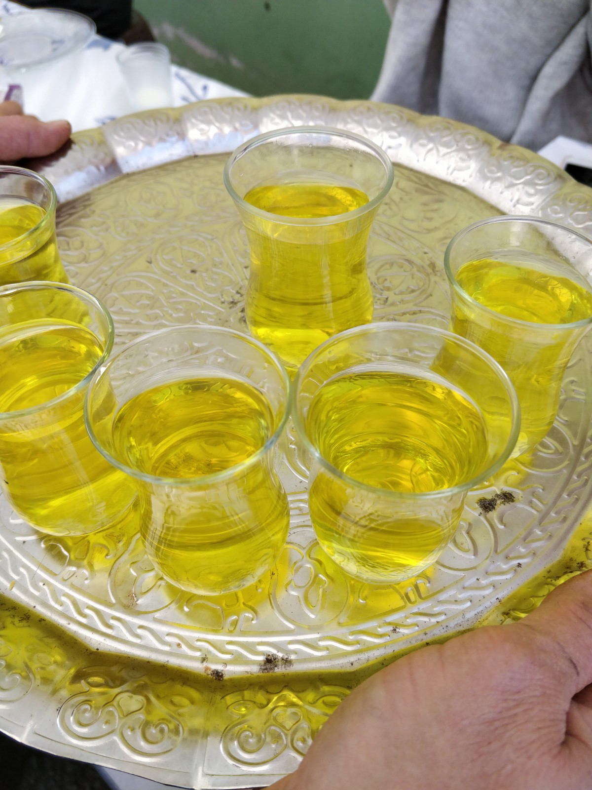 Sarı içecek dolu cam bardaklar gümüş tepside servis ediliyor