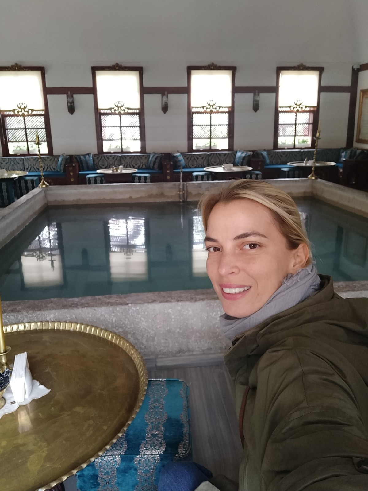 Geleneksel havuzlu iç mekanda gülümseyen kadın selfie çekiyor